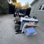 Alpine Junk Removal crew member at the trailer with a pile of household items ready to load